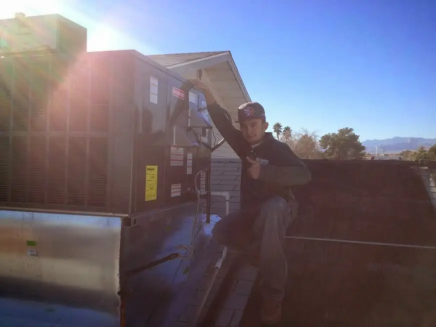 HVAC technician performing AC Tune-Up on a rooftop unit in Harvey